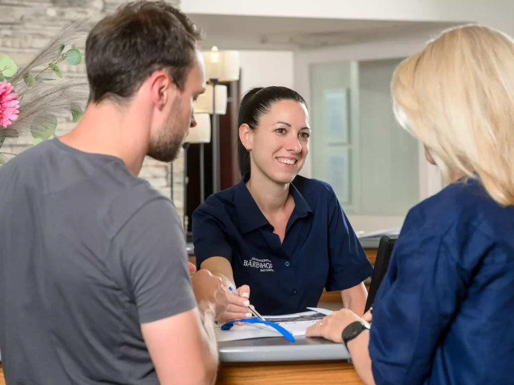 Freundlicher Empfang im Bärenhof Bad Gastein – ein Mitarbeiterteam unterstützt Gäste kompetent beim Check-in an der Rezeption.
