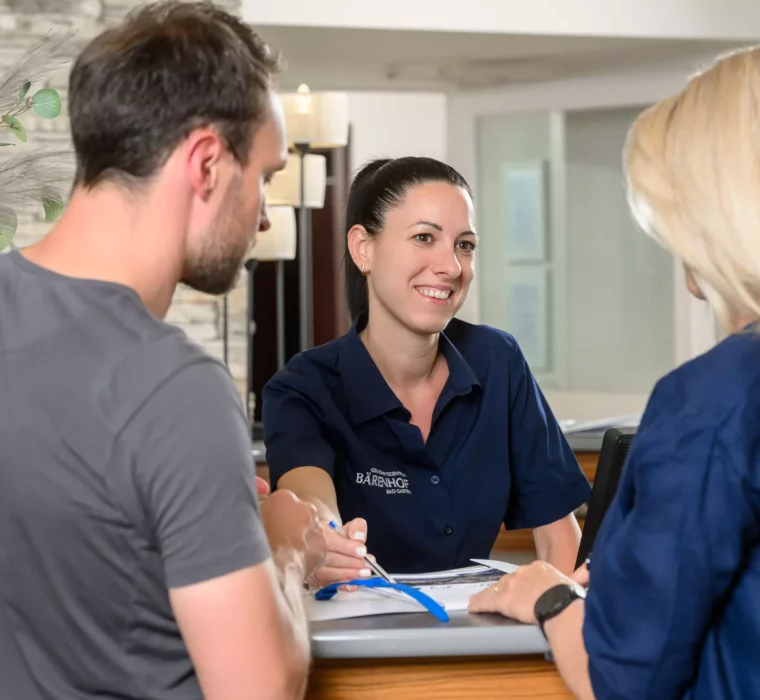 Freundlicher Empfang im Bärenhof Bad Gastein – ein Mitarbeiterteam unterstützt Gäste kompetent beim Check-in an der Rezeption.