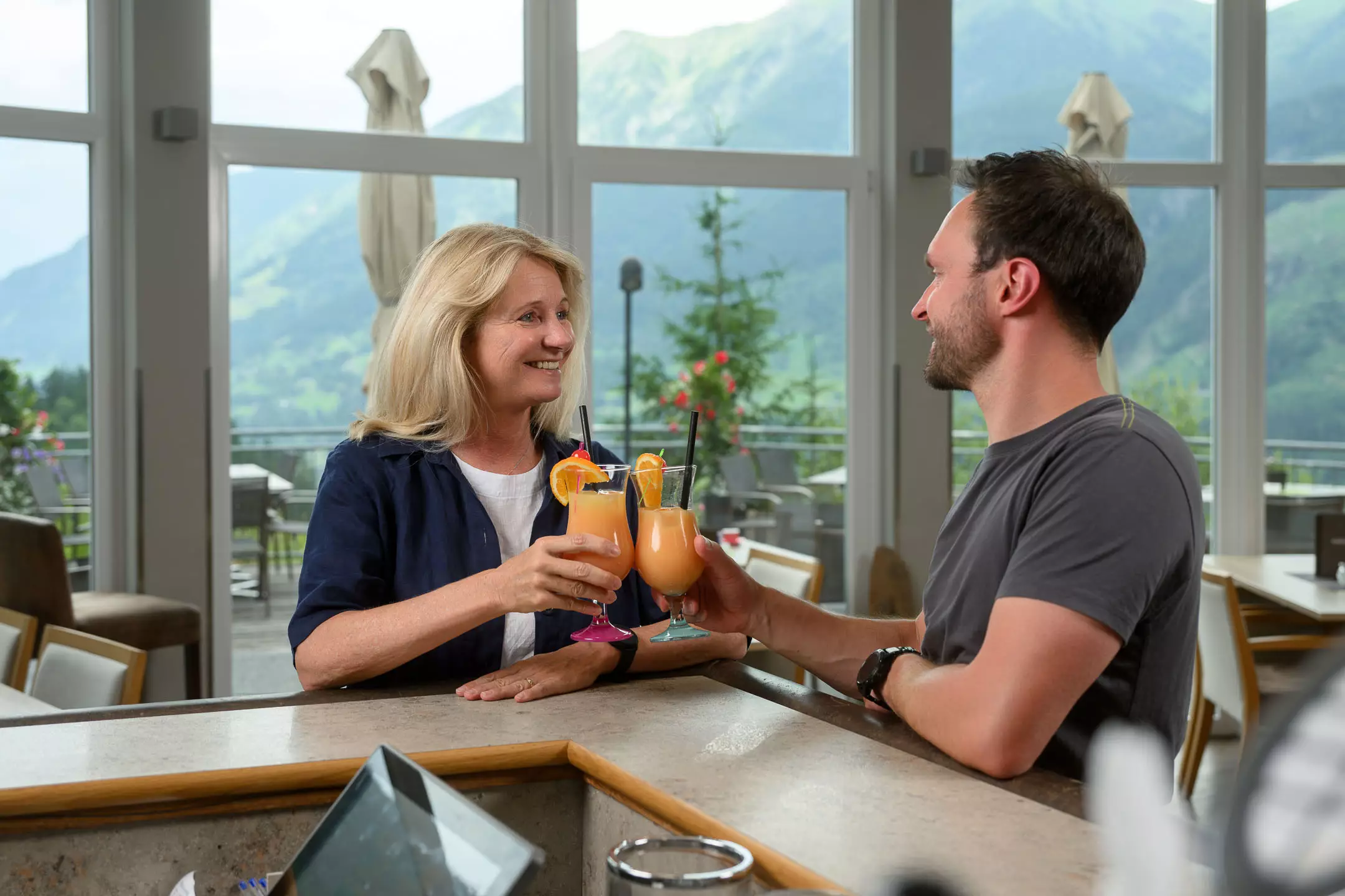 Gäste stoßen mit alkoholfreien Cocktails an der Bar im Felsencafé des Bärenhofs Bad Gastein an – entspannte Genussmomente mit Ausblick auf die Gasteiner Berge.
