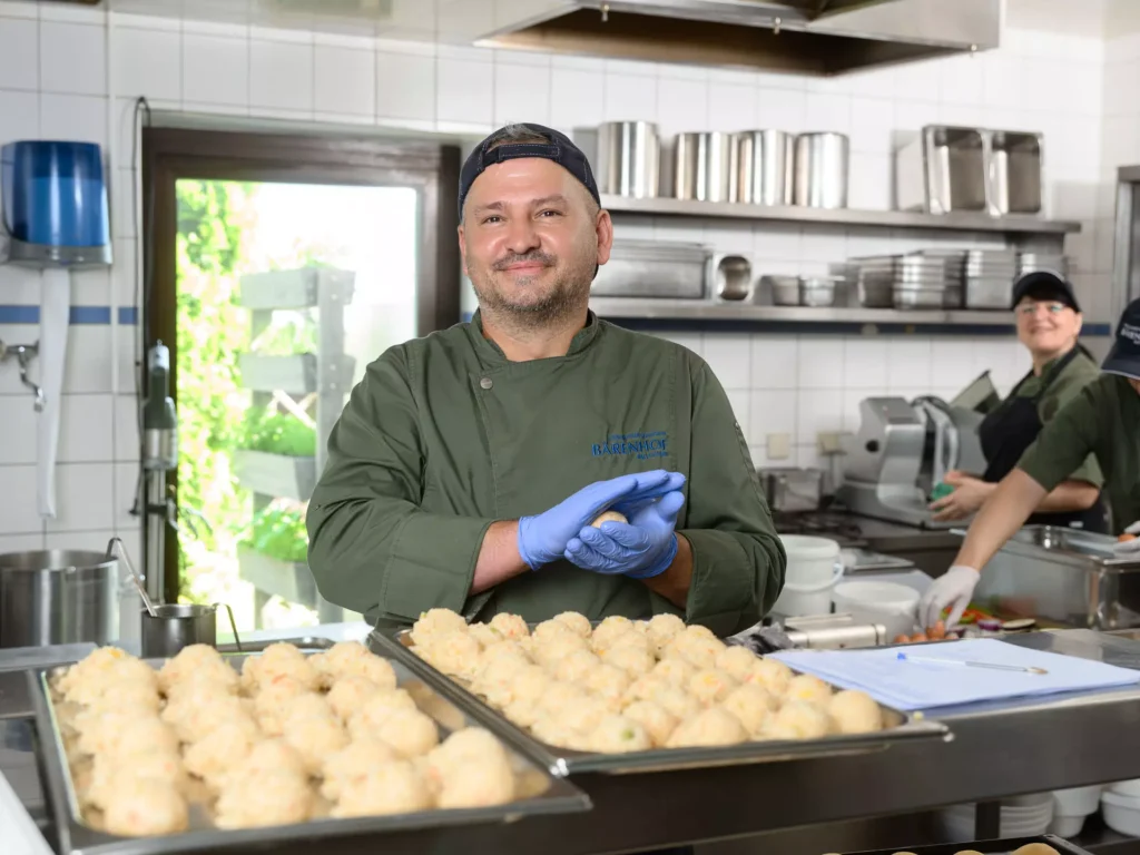 Ein Koch des Bärenhofs Bad Gastein bei der frischen Zubereitung von Knödeln – mit Liebe, Qualität und einem Lächeln für den gesunden Genuss.