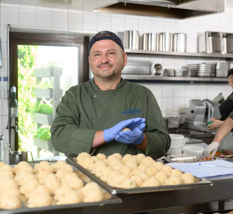 Ein Koch des Bärenhofs Bad Gastein bei der frischen Zubereitung von Knödeln – mit Liebe, Qualität und einem Lächeln für den gesunden Genuss.