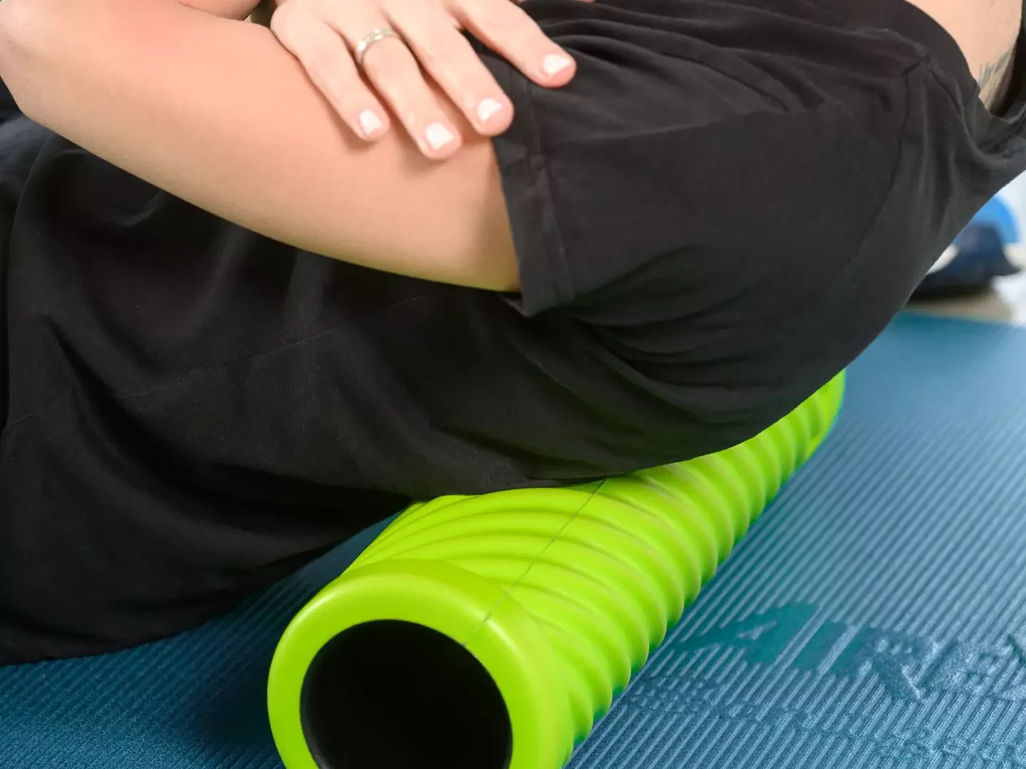 Nahaufnahme einer therapeutischen Rückenübung mit Faszienrolle zur Mobilisation der Brustwirbelsäule auf einer Gymnastikmatte.