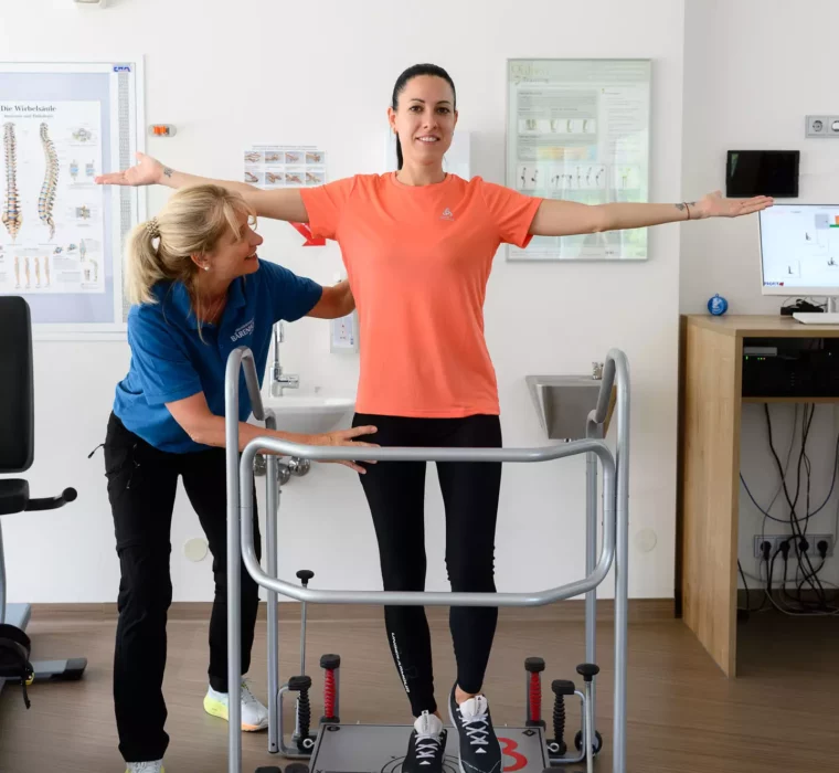 Therapeutin begleitet Patientin bei sensomotorischem Gleichgewichtstraining auf dem Posturomed im MTT-Raum des Bärenhofs.