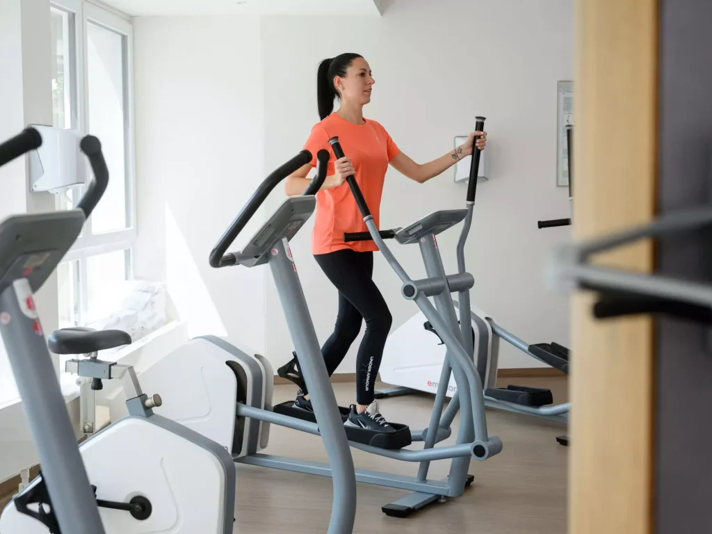 Frau trainiert im Fitnessbereich des Bärenhofs auf einem Crosstrainer zur Förderung von Ausdauer und Gelenkschonung.