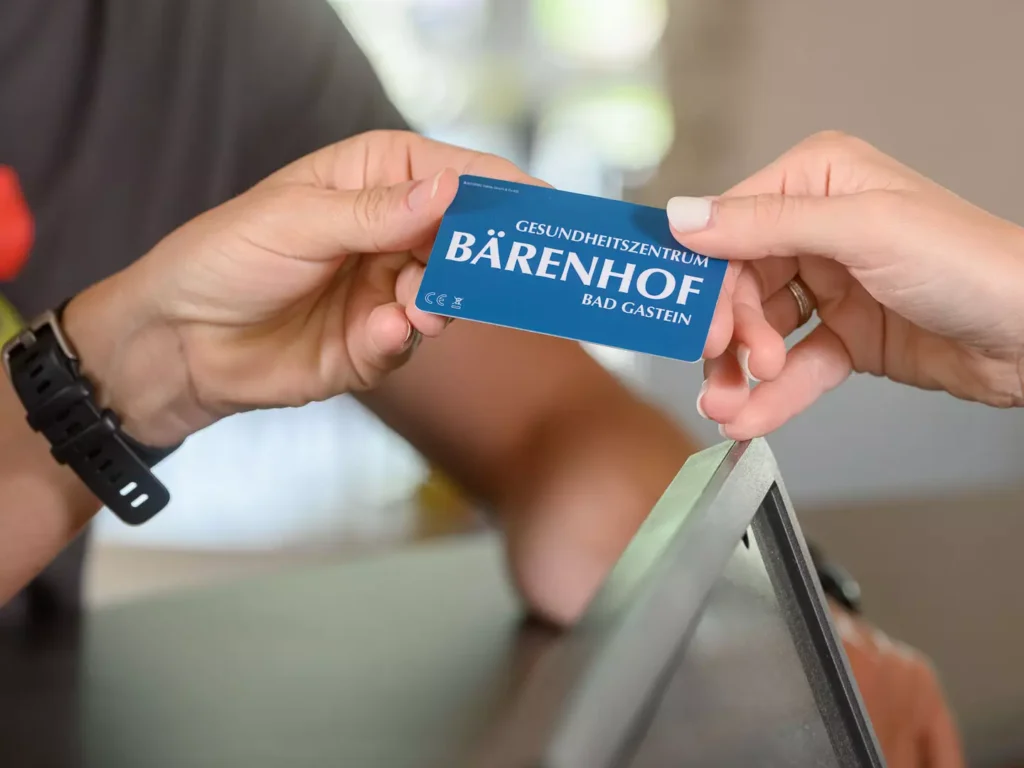Nahaufnahme beim Check-in im Bärenhof Bad Gastein – eine Gästehand nimmt die Schlüsselkarte des Gesundheitszentrums entgegen.