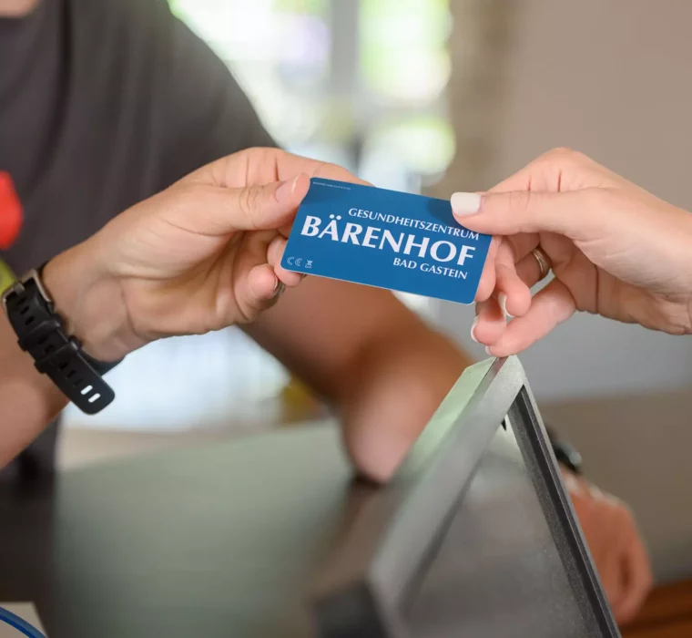 Nahaufnahme beim Check-in im Bärenhof Bad Gastein – eine Gästehand nimmt die Schlüsselkarte des Gesundheitszentrums entgegen.