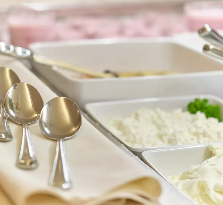 Drei Löffel auf weißer Serviette neben Schalen mit Quark und anderen Frühstückszutaten im Kurhotel Bärenhof Bad Gastein