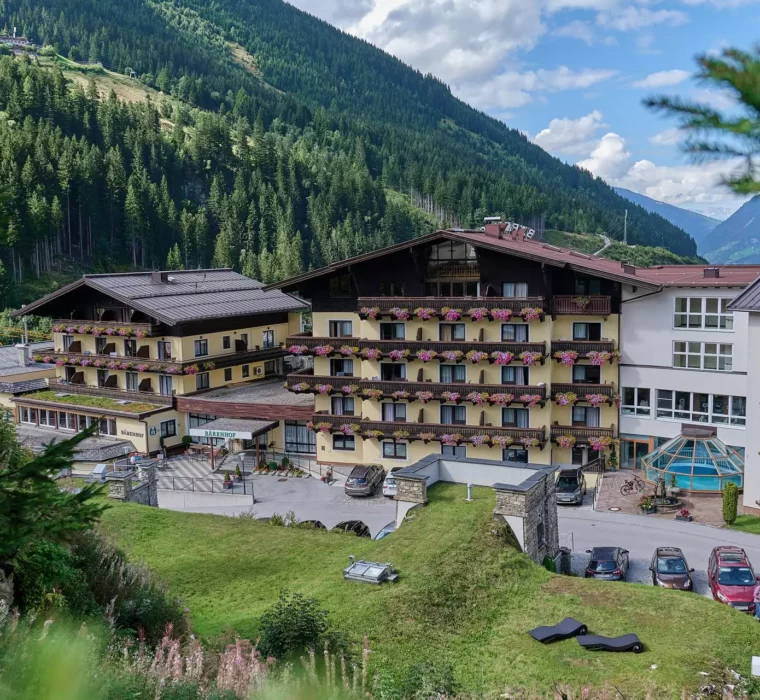 Gesundheitszentrum Kurhotel Bärenhof in Bad Gastein mit Blumen geschmückten Balkonen und Bergen im Hintergrund