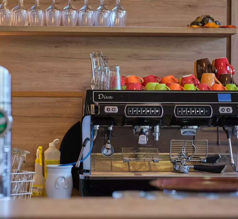 Moderne Espressomaschine mit bunten Kaffeetassen und Gläsern in einem Café im Gesundheitszentrum Bärenhof Bad Gastein.