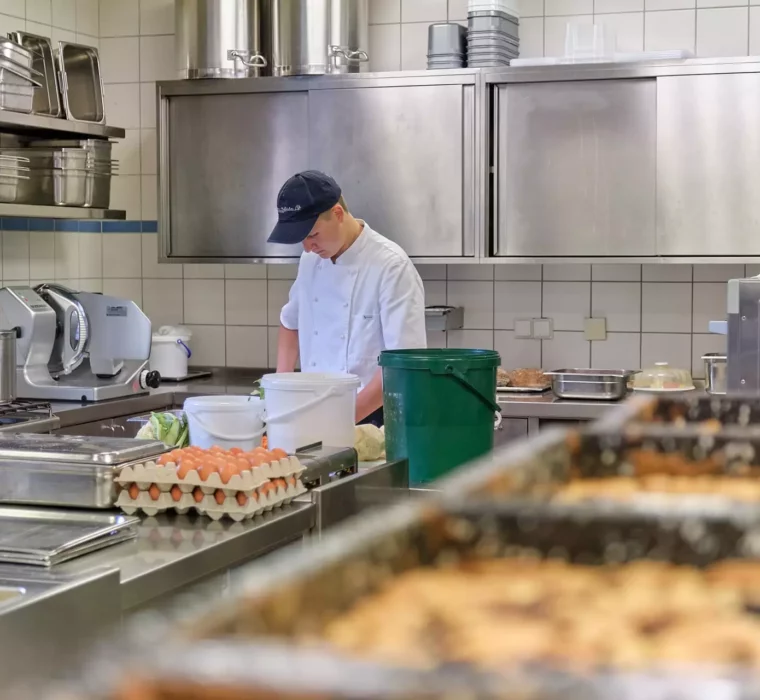 Koch in weißer Uniform arbeitet in der professionellen Küche des Gesundheitszentrums Bärenhof Bad Gastein mit Eiern und