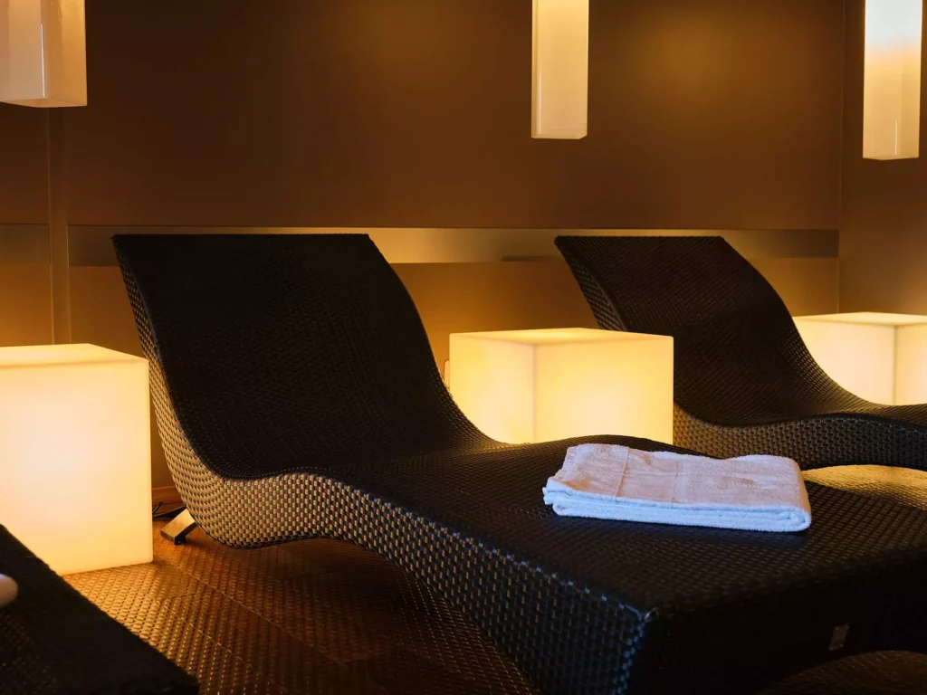 Dunkle Relaxliegen mit weißen Handtüchern in gedämpft beleuchtetem Wellnessbereich im Gesundheitszentrum Bärenhof Bad Gastein