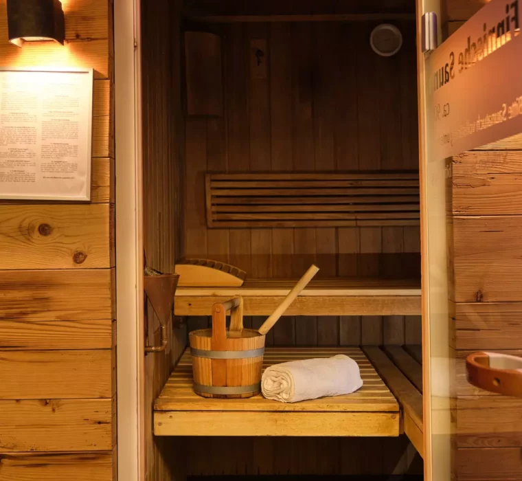 Holzsauna mit Holzeimer, Schöpfkelle und weißem Handtuch im Gesundheitszentrum Bärenhof Bad Gastein