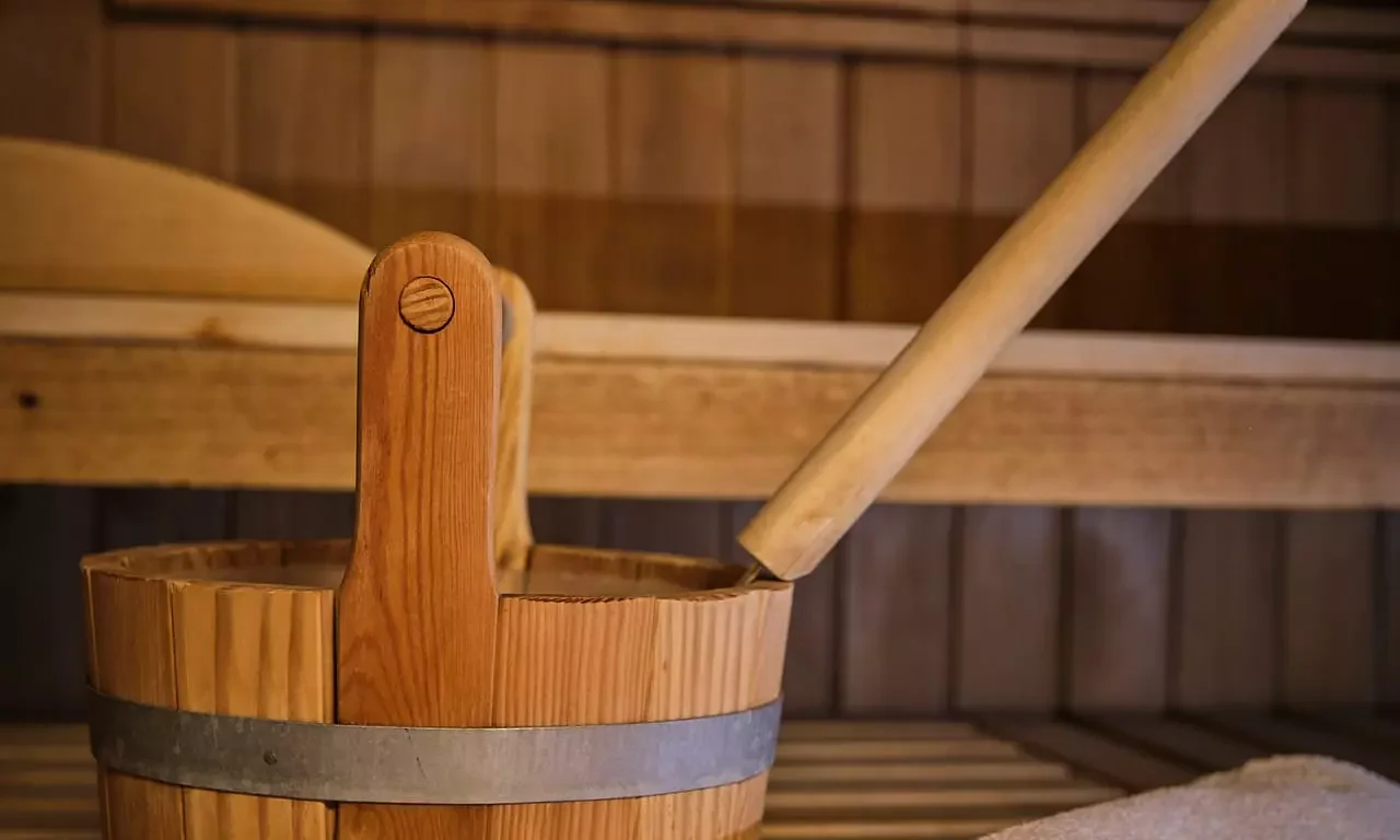 Holzeimer mit Kelle und zusammengerolltes Handtuch in einer Sauna im Gesundheitszentrum Bärenhof Bad Gastein