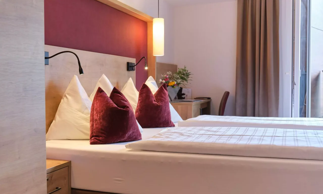 Modern eingerichtetes Doppelzimmer im Gesundheitszentrum Kurhotel Bärenhof Bad Gastein mit weißen und roten Kissen und