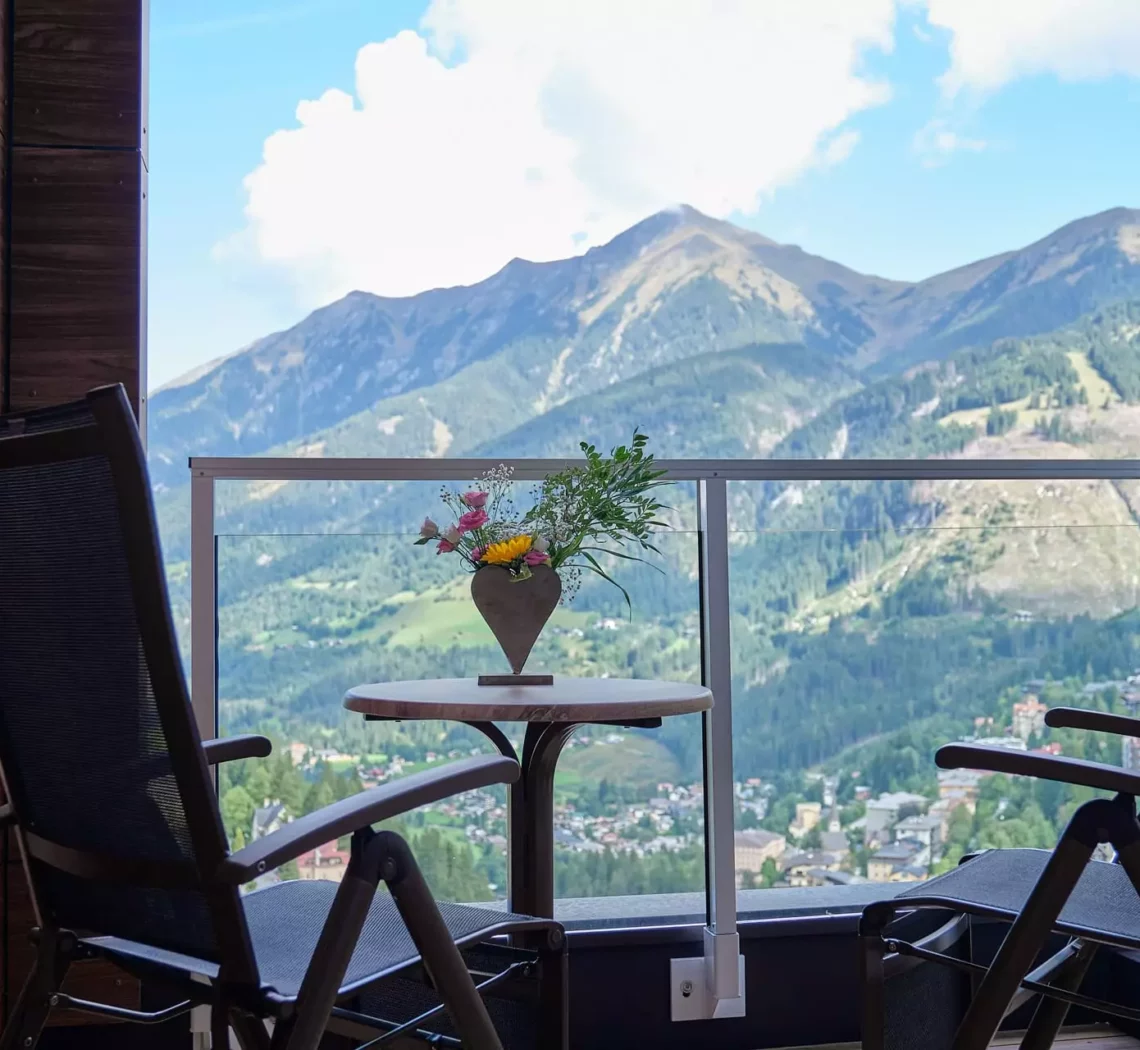 Balkon mit zwei Stühlen und Tisch mit Blumendeko im Kurhotel Bärenhof Bad Gastein mit Bergblick zur Erholung und Genesung.