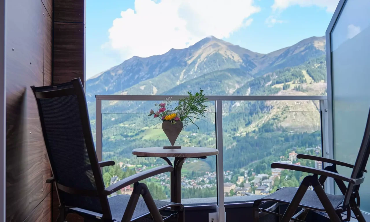 Balkon mit zwei Stühlen und Tisch mit Blumendeko im Kurhotel Bärenhof Bad Gastein mit Bergblick zur Erholung und Genesung.