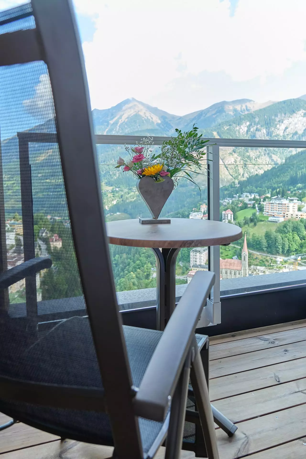 Balkon mit Stuhl und Tisch mit Blumenvase, Blick auf Berge und Ort Bad Gastein im Gesundheitszentrum Bärenhof