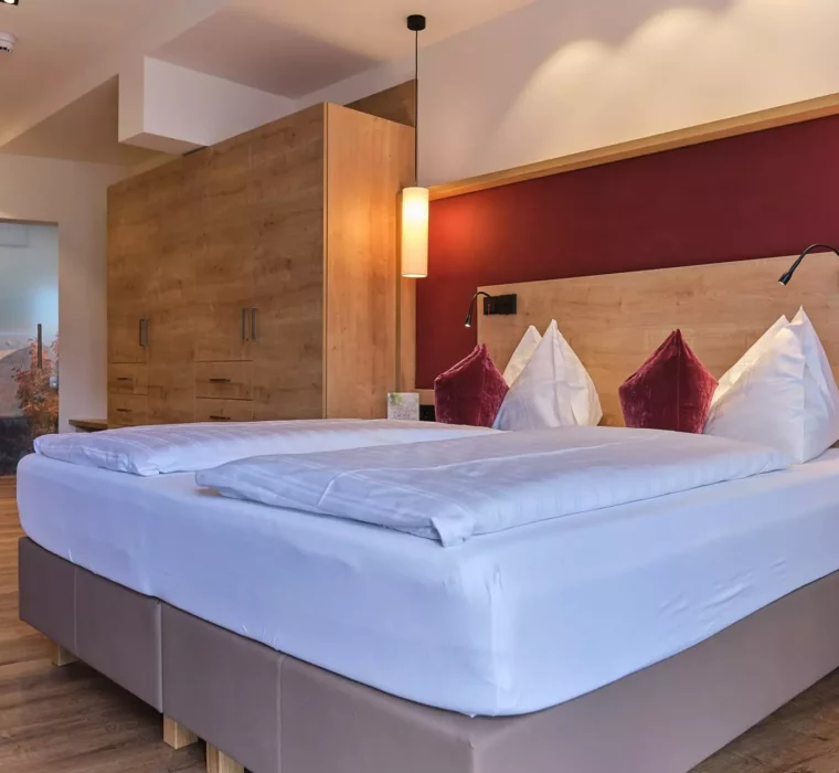Modern eingerichtetes Hotelzimmer mit Doppelbett, Holzmöbeln und warmen Farben im Gesundheitszentrum Bärenhof Bad Gastein