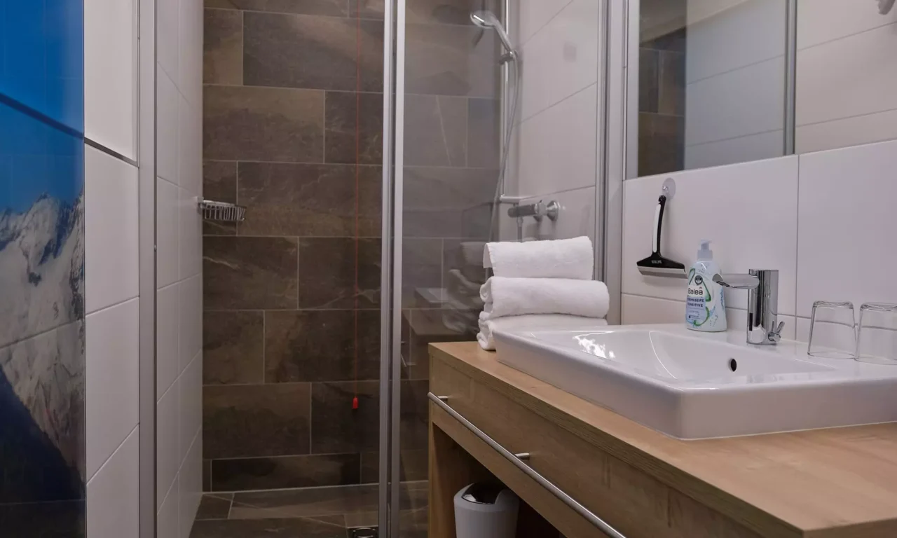 Modernes Badezimmer im Kurhotel Bärenhof Bad Gastein mit Dusche, Waschbecken, Handtüchern und Hygieneartikeln für