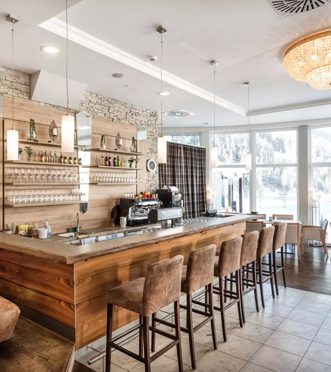 Helle Bar mit Holztheke und hohen Stühlen im Gesundheitszentrum Bärenhof Bad Gastein mit Panoramafenstern und Bergblick
