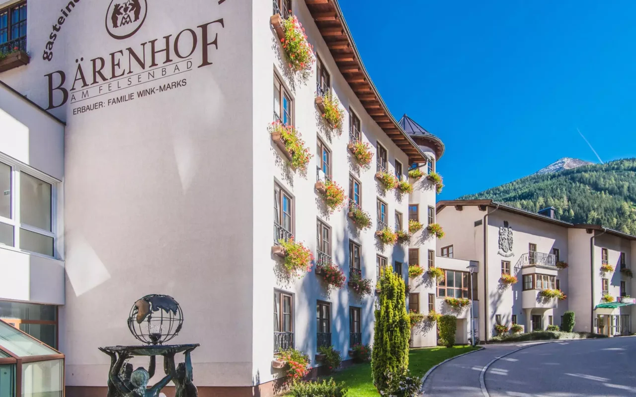 Außenaufnahme des Gesundheitszentrums Kurhotel Bärenhof in Bad Gastein mit Blumenschmuck an Fenstern und Bergkulisse im