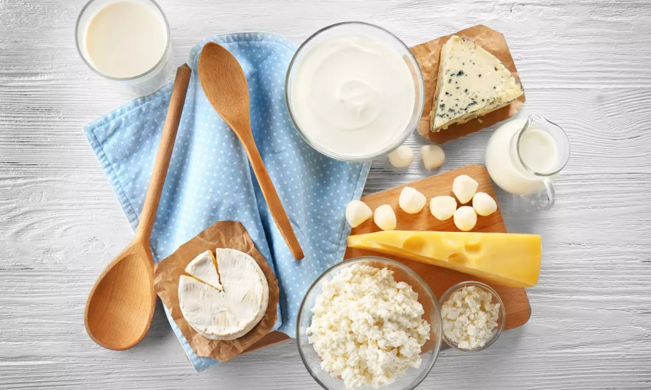 Verschiedene Käsesorten, Milch und Joghurt auf Holzbrett mit Holzlöffeln und blauem Tuch für gesunde Ernährung im Bärenhof