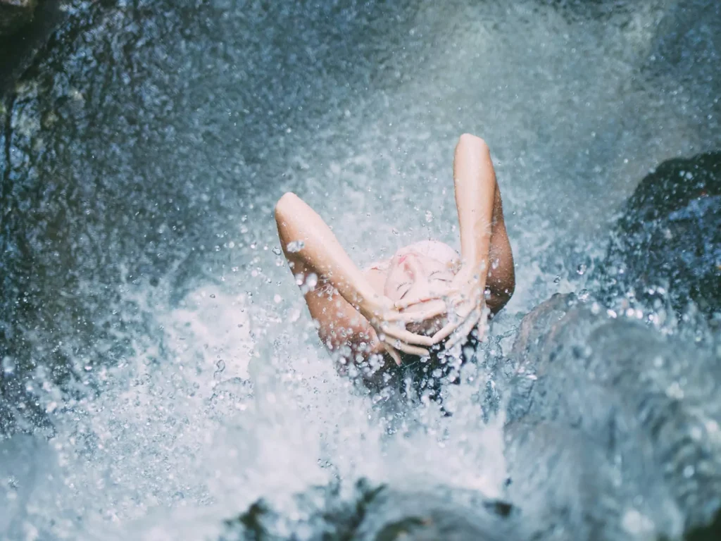 Person entspannt sich unter einem Wasserfall im Gesundheitszentrum Bärenhof Bad Gastein bei Radon-Therapie