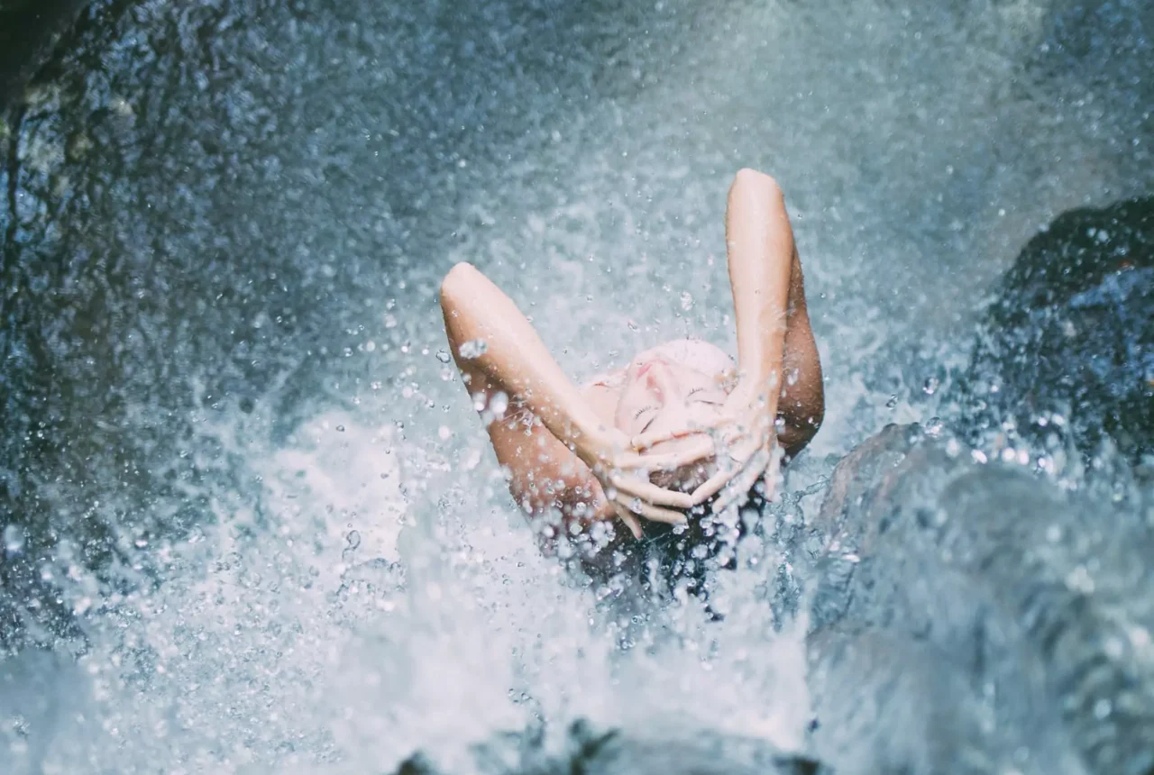 Person entspannt sich unter einem Wasserfall im Gesundheitszentrum Bärenhof Bad Gastein bei Radon-Therapie