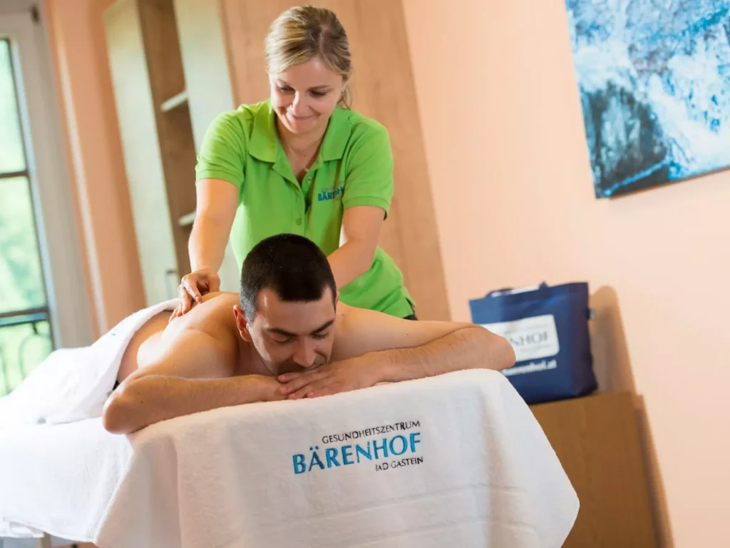 Mann erhält entspannende Rückenmassage im Gesundheitszentrum Bärenhof Bad Gastein während Kuraufenthalt zur Rehabilitation.