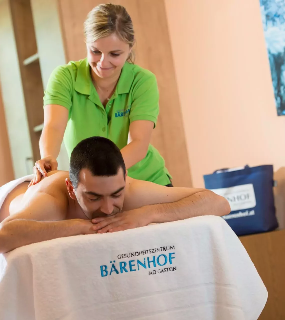 Mann erhält entspannende Rückenmassage im Gesundheitszentrum Bärenhof Bad Gastein während Kuraufenthalt zur Rehabilitation.