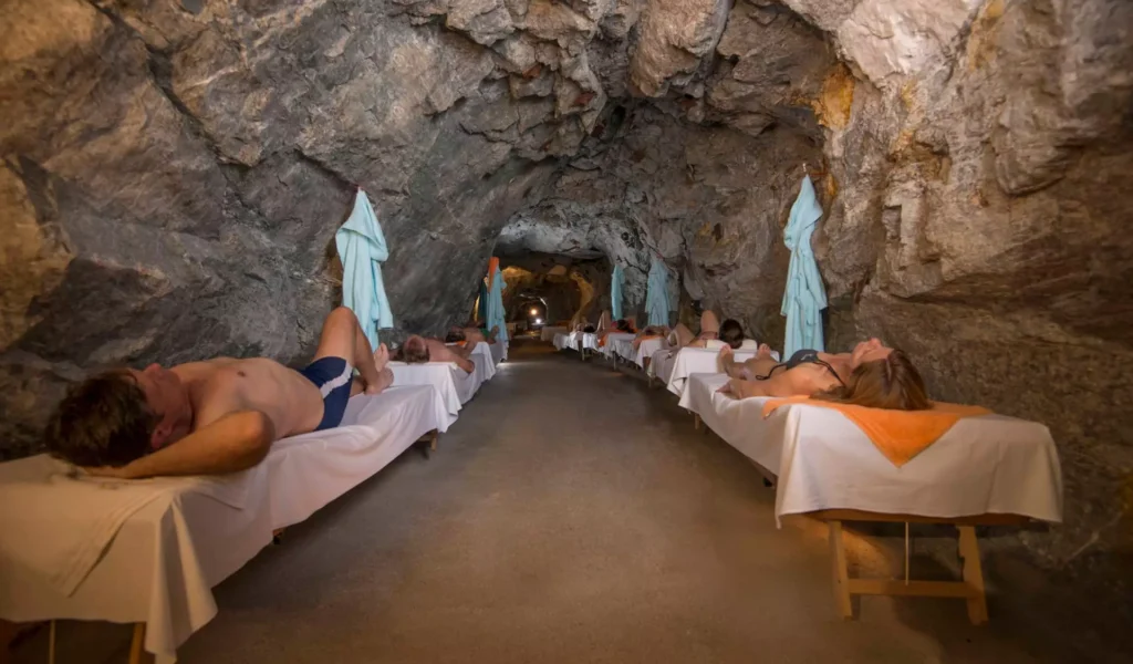 Entspannte Menschen liegen auf Liegen in einer natürlichen Felsenhöhle im Gesundheitszentrum Bärenhof Bad Gastein zur