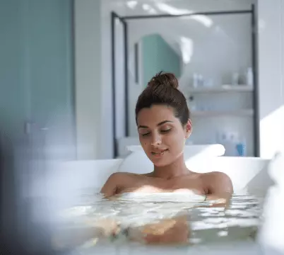 Frau entspannt in einer Badewanne in hellem Badezimmer, Symbol für Erholung und Kuraufenthalt im Gesundheitszentrum Bärenhof